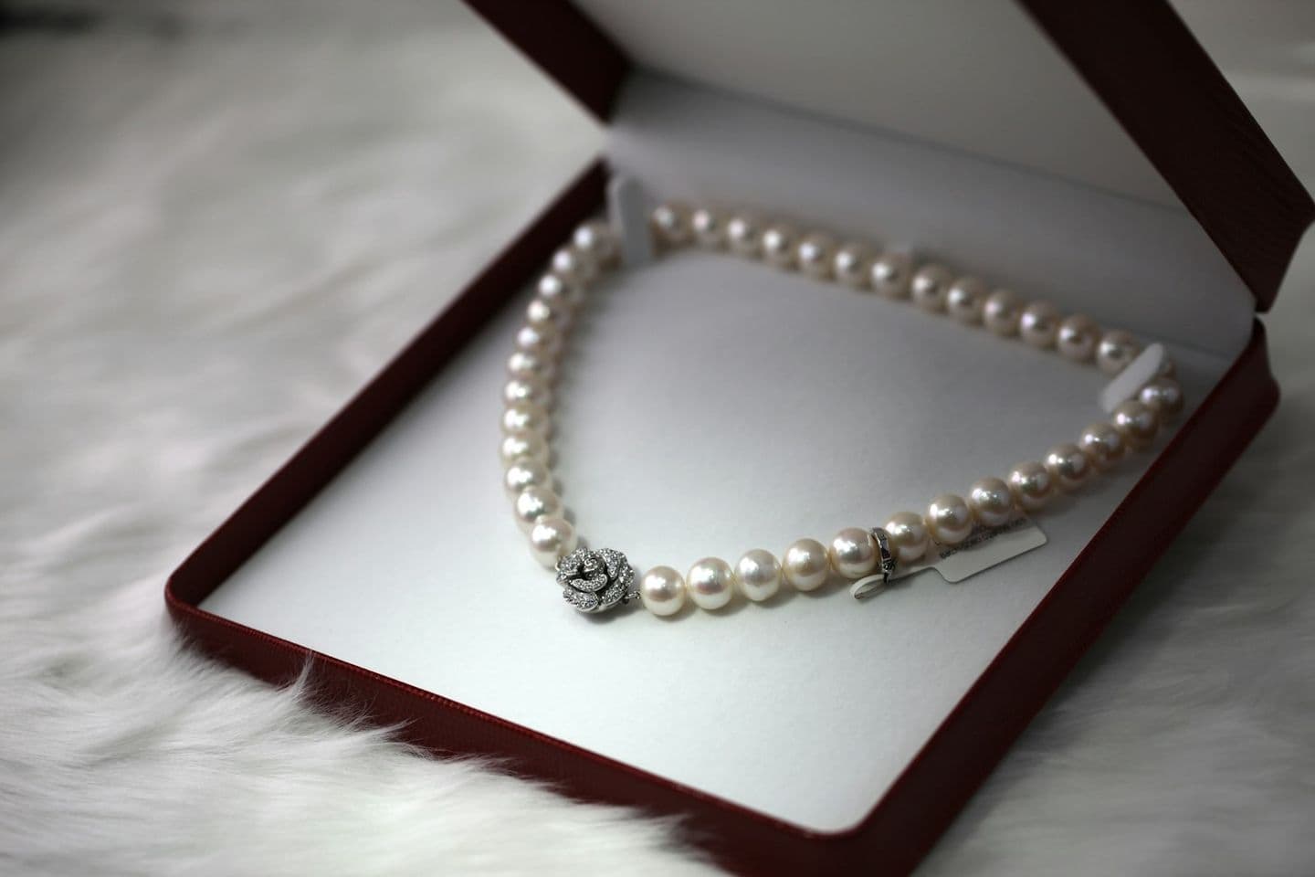 A pearl necklace in an open red jewellery box