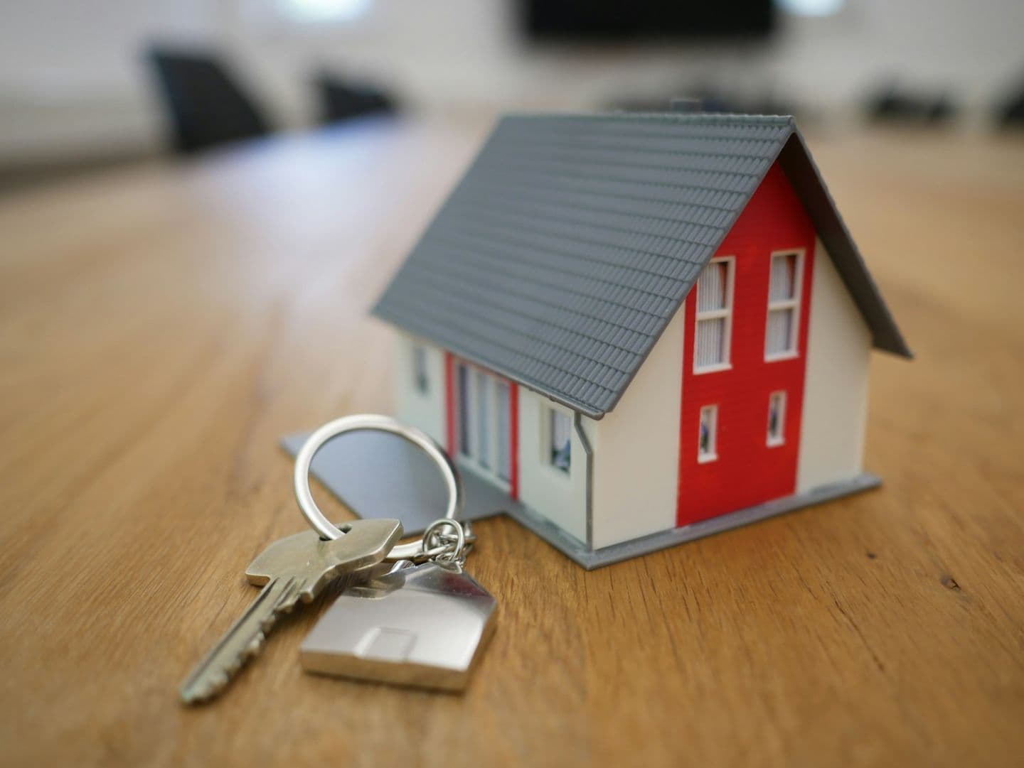 A small model house and a set of keys on a wooden table